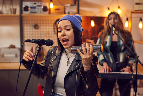 Young woman singing and playing musical instrument in studio