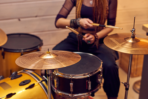 Drum set and young female with drumsticks sitting near by
