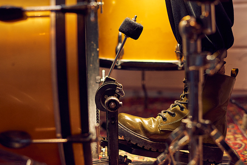 Part of leg of drummer on pedal of drum kit in studio