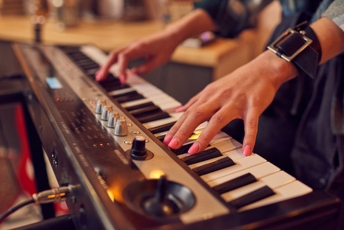 Hands of young female touching keys of synthesizer