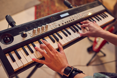 Young woman playing synthesizer in studio of sound records