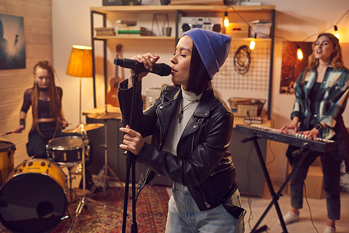 Young female singer and her band recording new songs in their studio