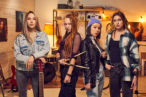 Girl band consisting of four females standing in row in studio