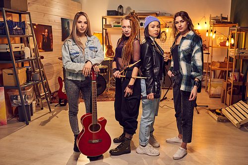 Four young women in casualwear standing in large modern sound recording studio