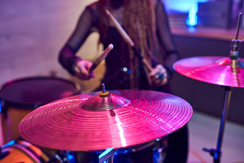 Cymbals of drum kit with female musician with drumsticks on background