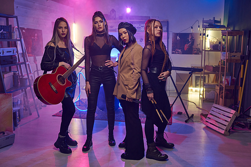 Group of young women with musical instruments standing in studio