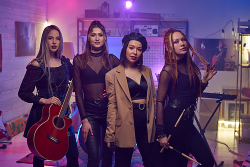 Four participants of modern girl band posing in sound recording studio