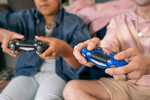 Two contemporary teenagers pressin buttons of joysticks while playing video game