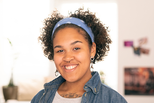 Pretty female teenager in casualwear looking at you with toothy smile