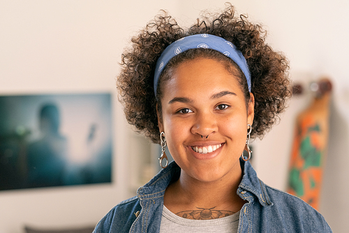 Cheerful teenage girl in casualwear looking at you with smile in home environment