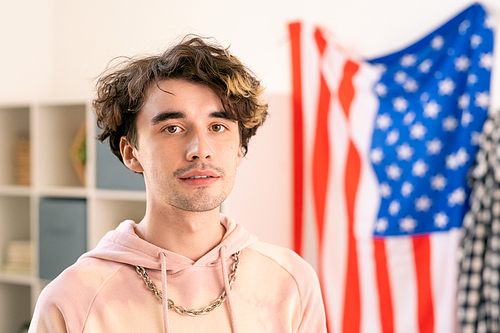 Teenage guy in pink hoodie standing in front of camera in home environment