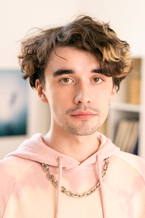 Serious teenage male in pink casualwear looking at camera