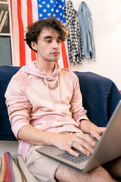 American teenage student using laptop while doing homework in his room