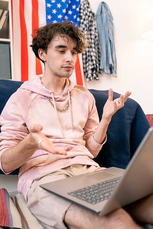 Contemporary teenager discussing homework with classmate in video chat in front of laptop