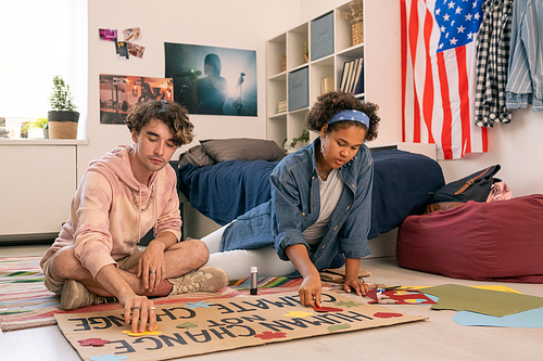 Two teenage designers working over climate project paper in home environment