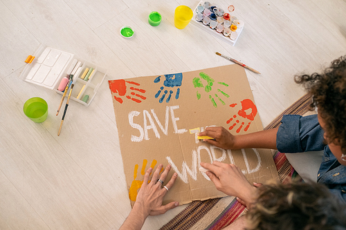 Two teenage college students drawing poster with slogan about saving world