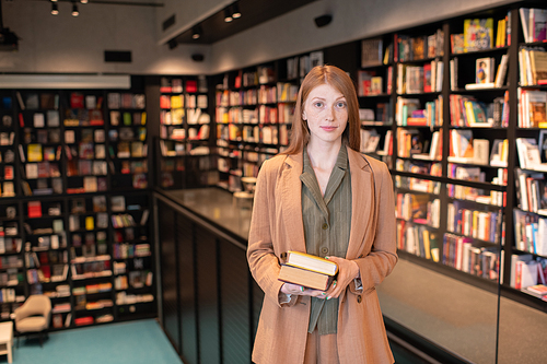 Pretty young student or businesswoman with books looking at camera