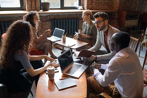 Two groups of co-workers discussing new ideas at meeting