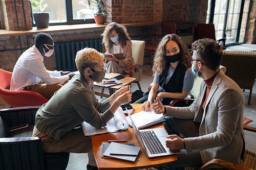 Group of young managers in protective masks working over new business project