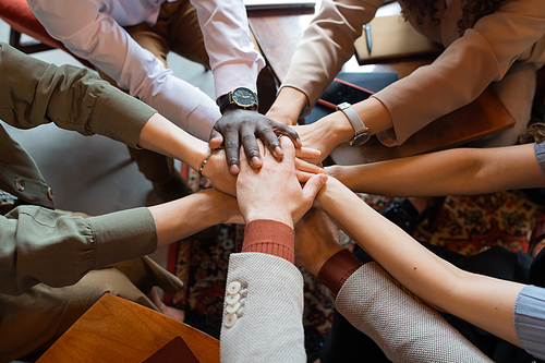 Arms of multiracial colleagues making pile of hands as symbol of companionship