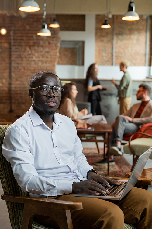 Young businessman working in the net while his colleagues discussing working points on background