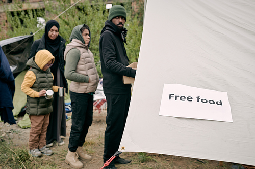 Queue of migrants standing in front of volunteering tent to get some free food