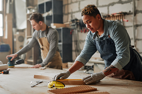 Warm toned portrait of artisan carpenters sanding wood and building handmade furniture pieces in workshop, copy space