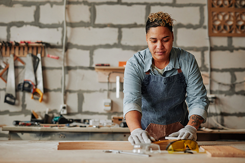 Warm toned portrait of Latin American female carpenter building handmade furniture piece in workshop, copy space