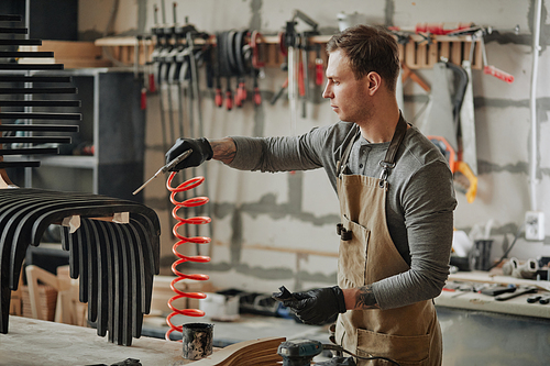 Side view portrait of young carpenter building designer furniture in workshop, copy space