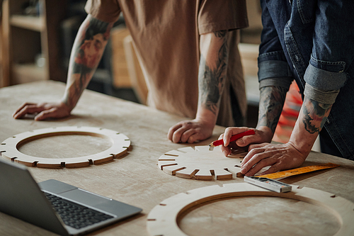 Closeup of two artisan shop owners designing wooden pieces in workshop, copy space