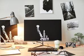 Background image of editors workplace with computer and black and white photos on walls, copy space