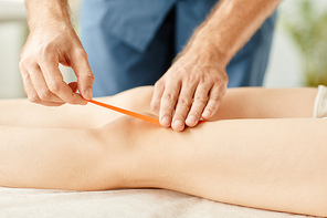 Close up of physiotherapist putting tape on knees of young woman to relieve muscle and joint pain, copy space