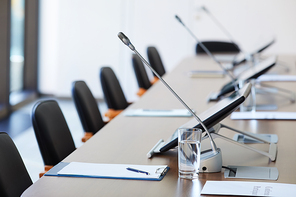 Image of empty table with documents and microphones at board room