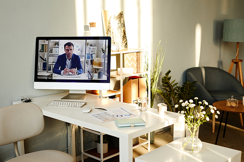 Modern desktop computer with paused video of successful businessman on screen in comfortable office interior