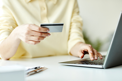 Unrecognizable woman buying something in online shop on laptop paying for items with credit card