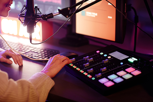 Unrecognizable woman preparing to to record podcast adjusting sound settings using mixing console