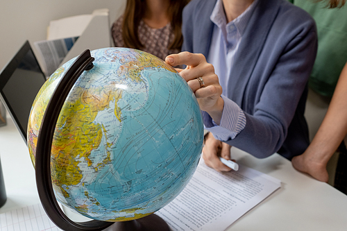 Hand of geography teacher pointing at continent on globe during lesson