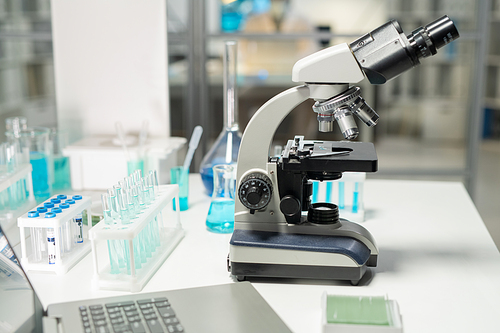 Workplace of contemporary researcher or scientist in clinic laboratory equipped with microscope, flasks and laptop