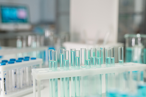 Group of test tubes containing light blue liquid substance standing on workplace of contemporary clinician or scientist