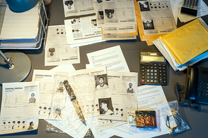 Part of workplace of contemporary fbi agent with criminal profiles, calculators, telephone, packets with clues and other stuff