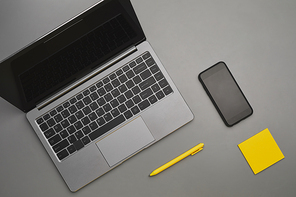 Graphic gray and yellow background of laptop and smartphone with business accessories at desk, flatlay top down view, copy space