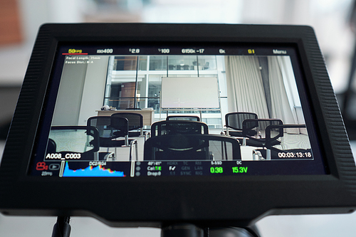 Display of video camera standing behind rows of black chairs and whiteboard in spacious conference hall or auditorium