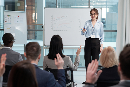 Confident speaker or business coach asking audience questions at seminar after presentation of upgraded financial information