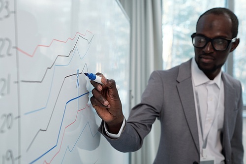 Hand of young African American speaker with highlighter pointing at company income graph during presentation at conference