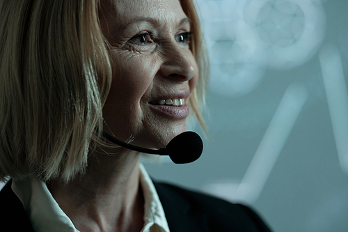 Face of happy mature businesswoman with microphone by her chin standing against interactive oard with sketches during speech