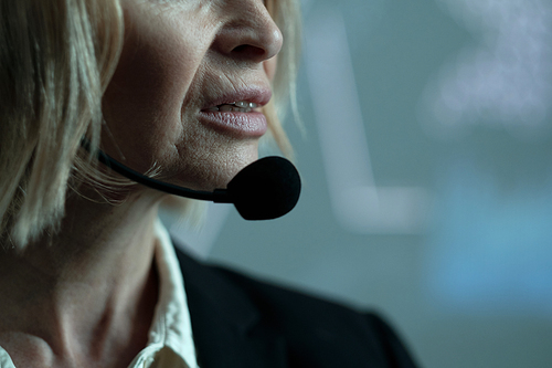 Part of face of mature confident female broker speaking in microphone in front of camera during report about economic situation