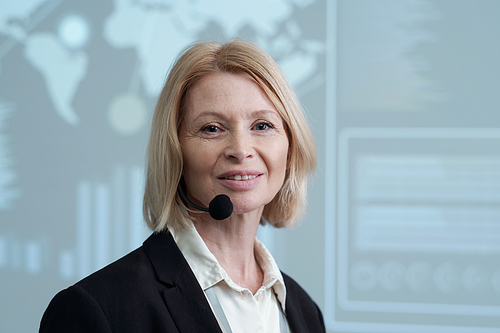 Happy experienced female broker with microphone by her mouth looking at camera while making speech about marketing analysis