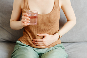 Closeup of young woman suffering from period cramps and holding hand on stomach, copy space