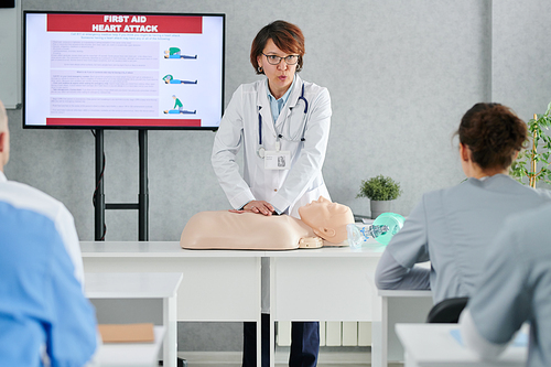 Medical specialist demonstrating on mannequin how to providing first aid to students at training