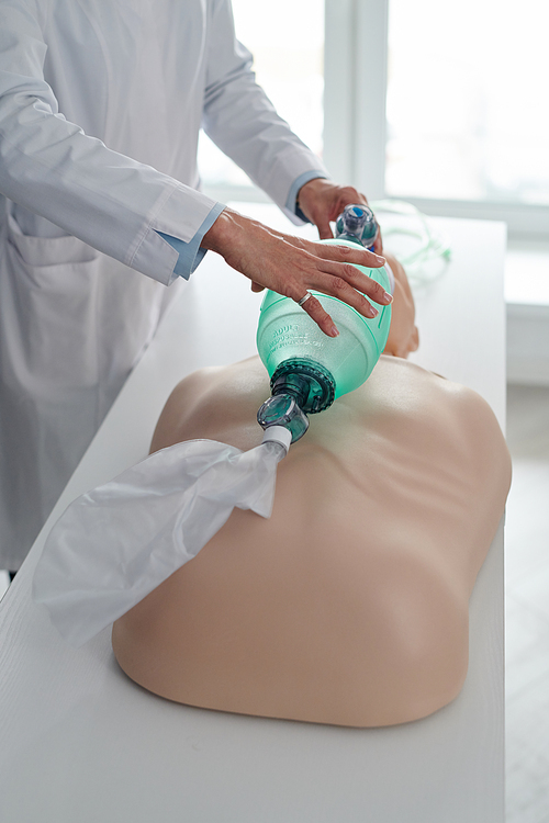 Close-up of medical instructor showing how to provide first aid to the victim using a breathing bag